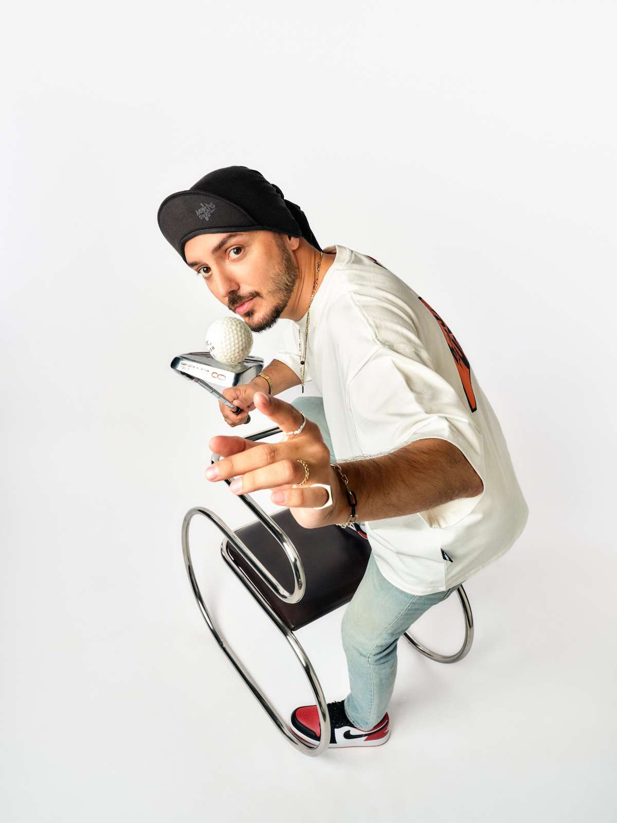 Hey! Douglas, İstanbul Çorbası koleksiyonu fotoğraf çekiminde. Üstünde beyaz renkli bir tişört var. Elinde golf sopası var.